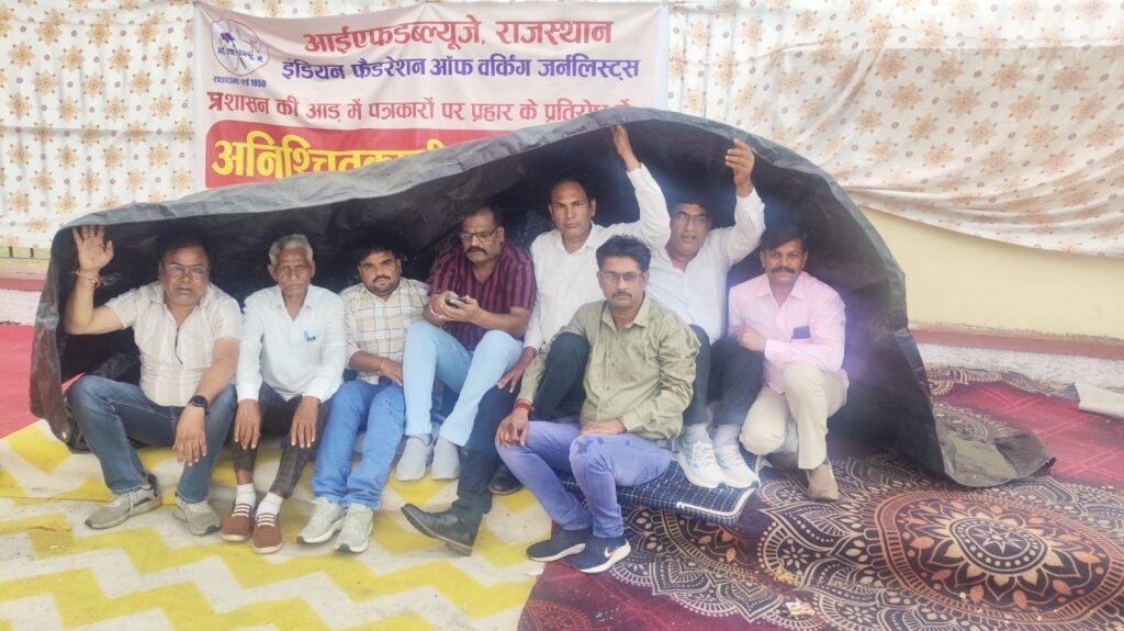 पत्रकार की आजीविका पर बुलडोजर और झूठे मुकदमों के विरोध में IFWJ संगठन द्वारा लगातार जारी है धरना